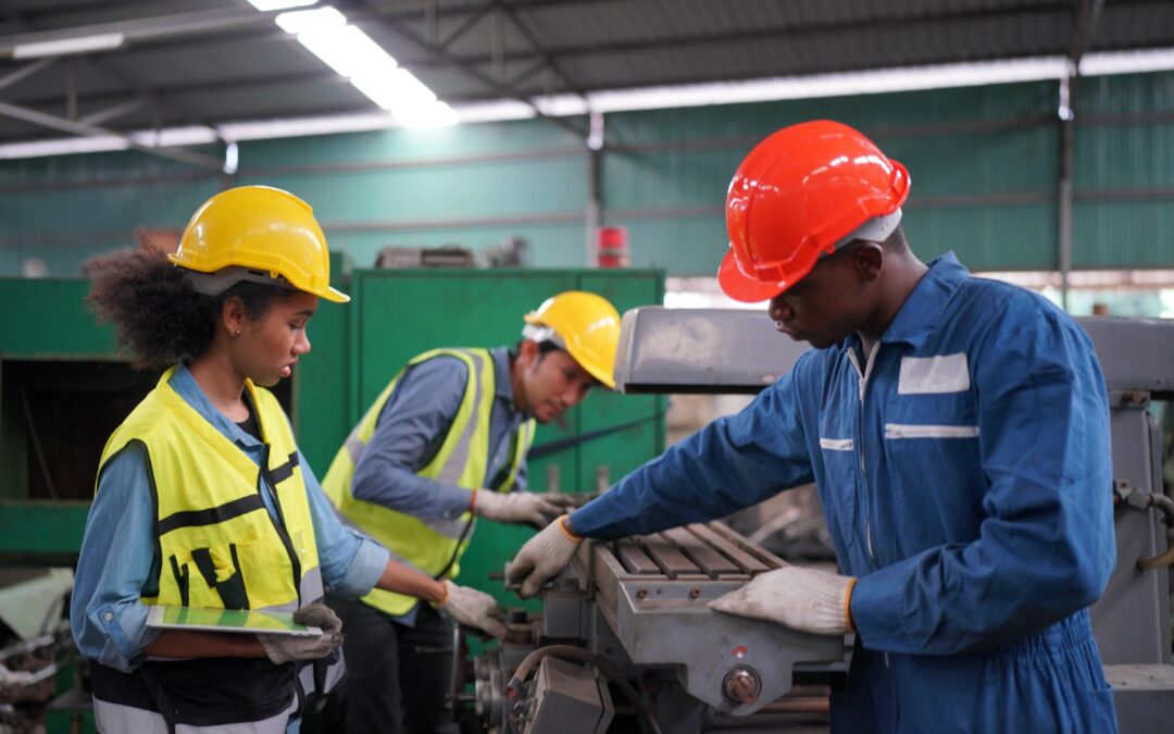 two factory workings looking at a machine and following work instructions via their digital device